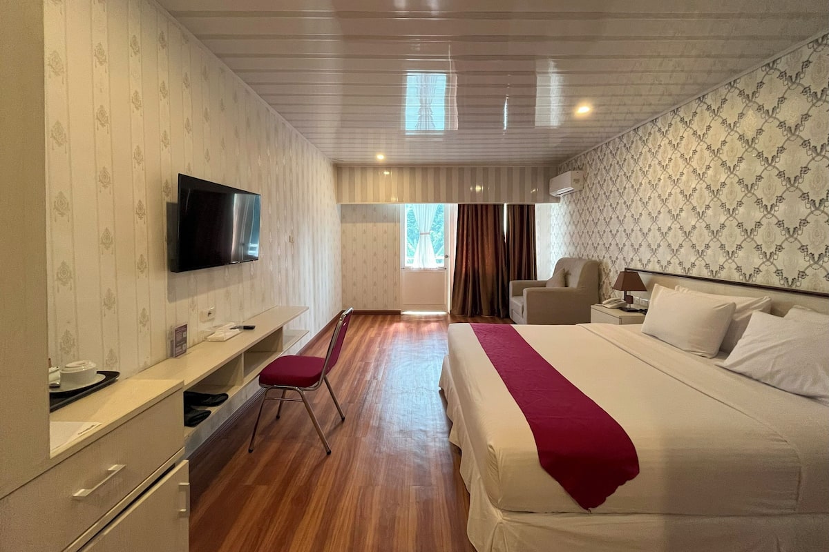 Una habitación de hotel con cama, televisión, escritorio y silla.