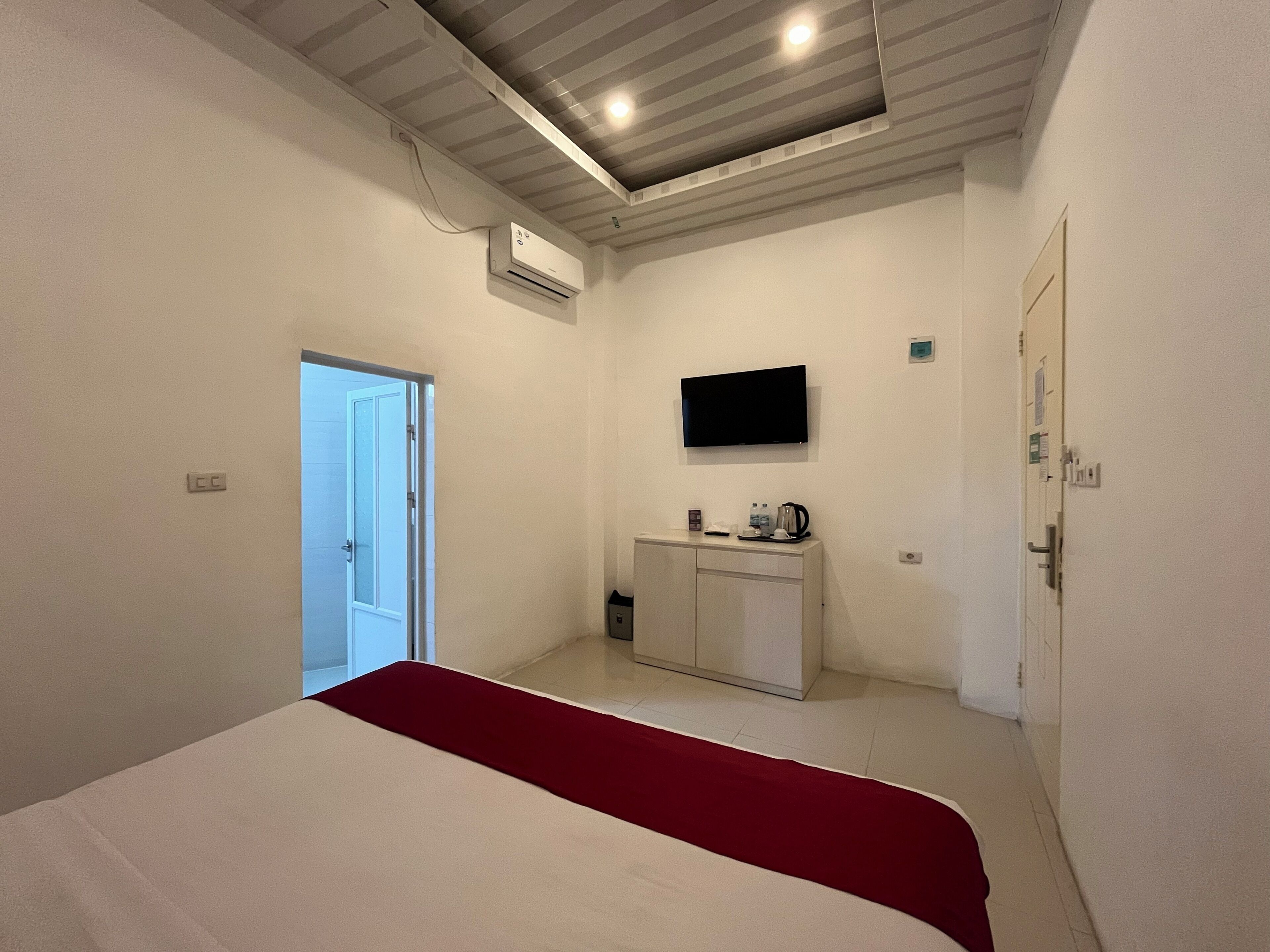 Un dormitorio con cama, televisión, minibar y aire acondicionado.