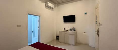 Un dormitorio con cama, televisión, minibar y aire acondicionado.