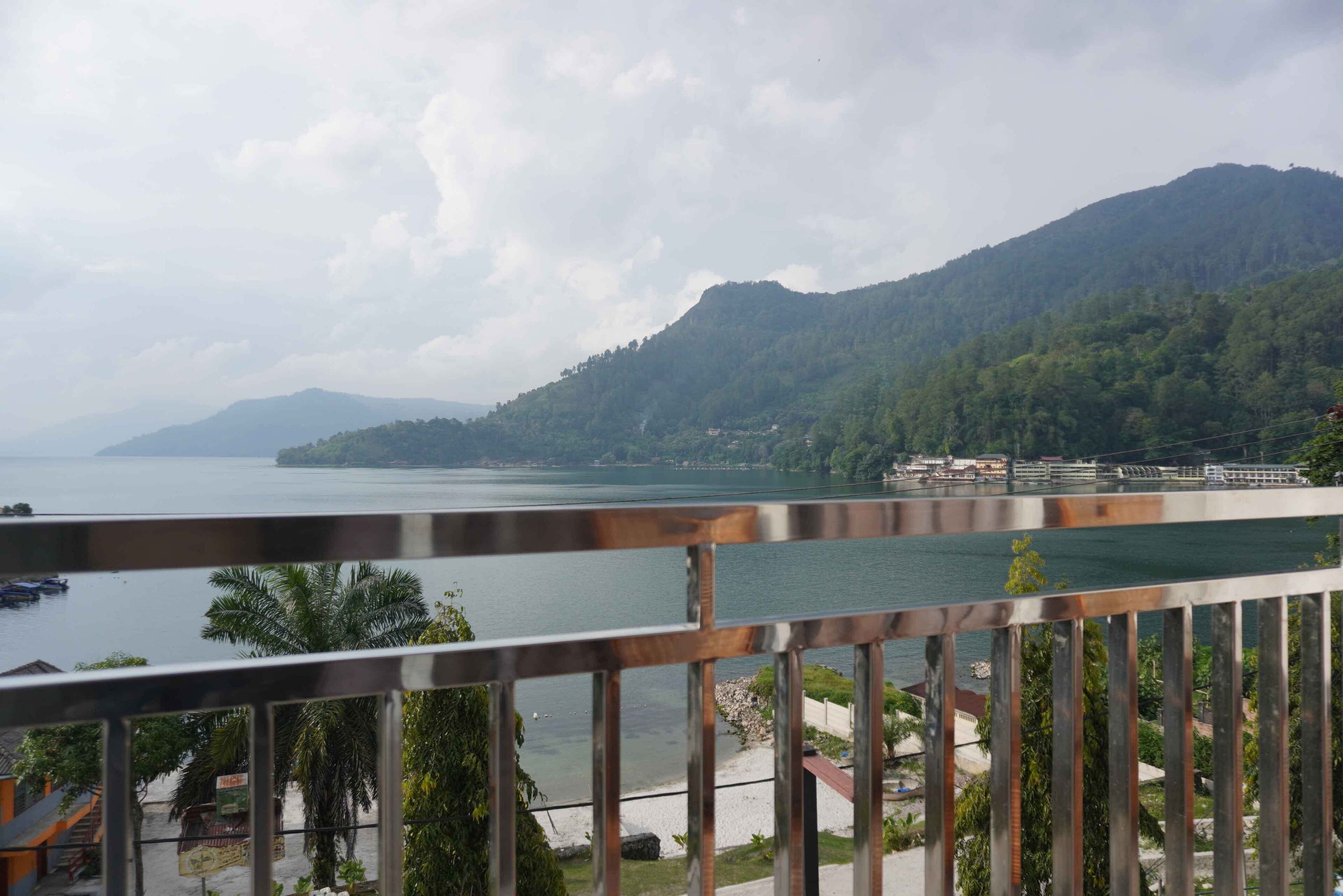 A coastal view with a mountain in the background, a body of water, and a wooden railing in the foreground.