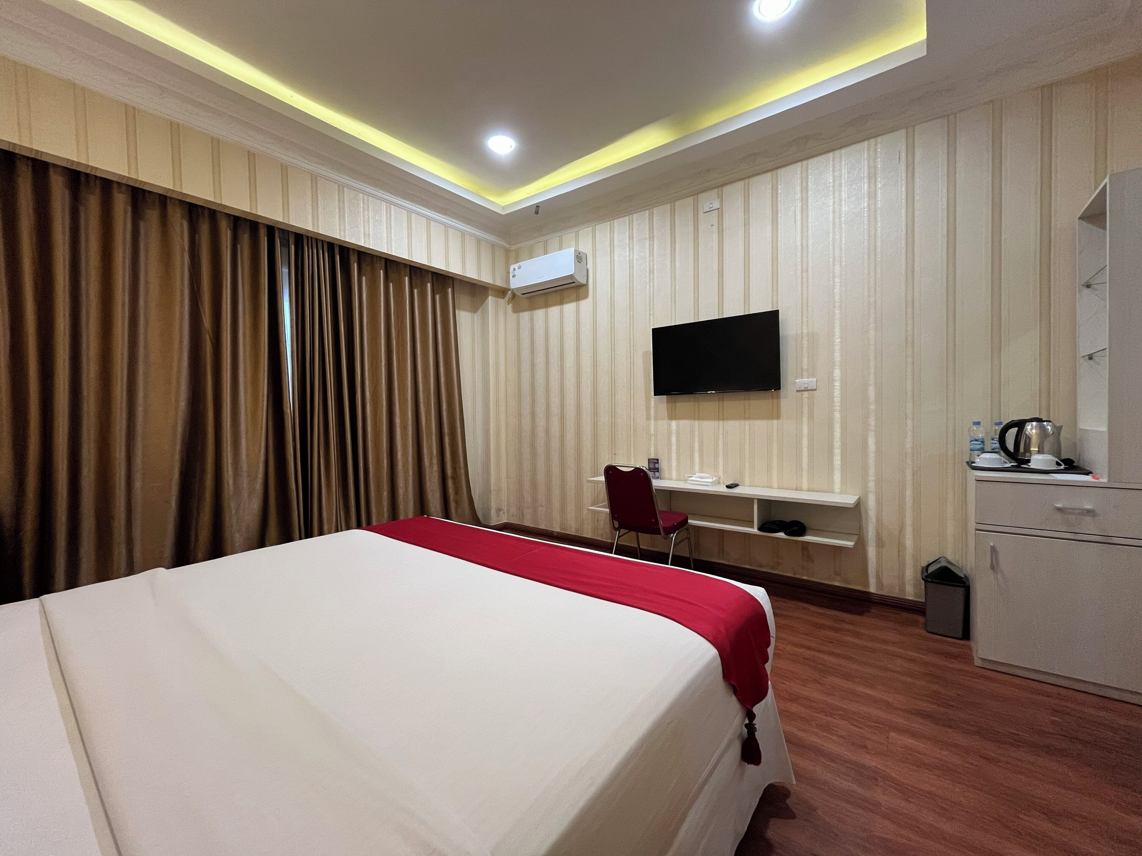 A hotel room with a bed, a desk, a chair, a television, and a wardrobe.