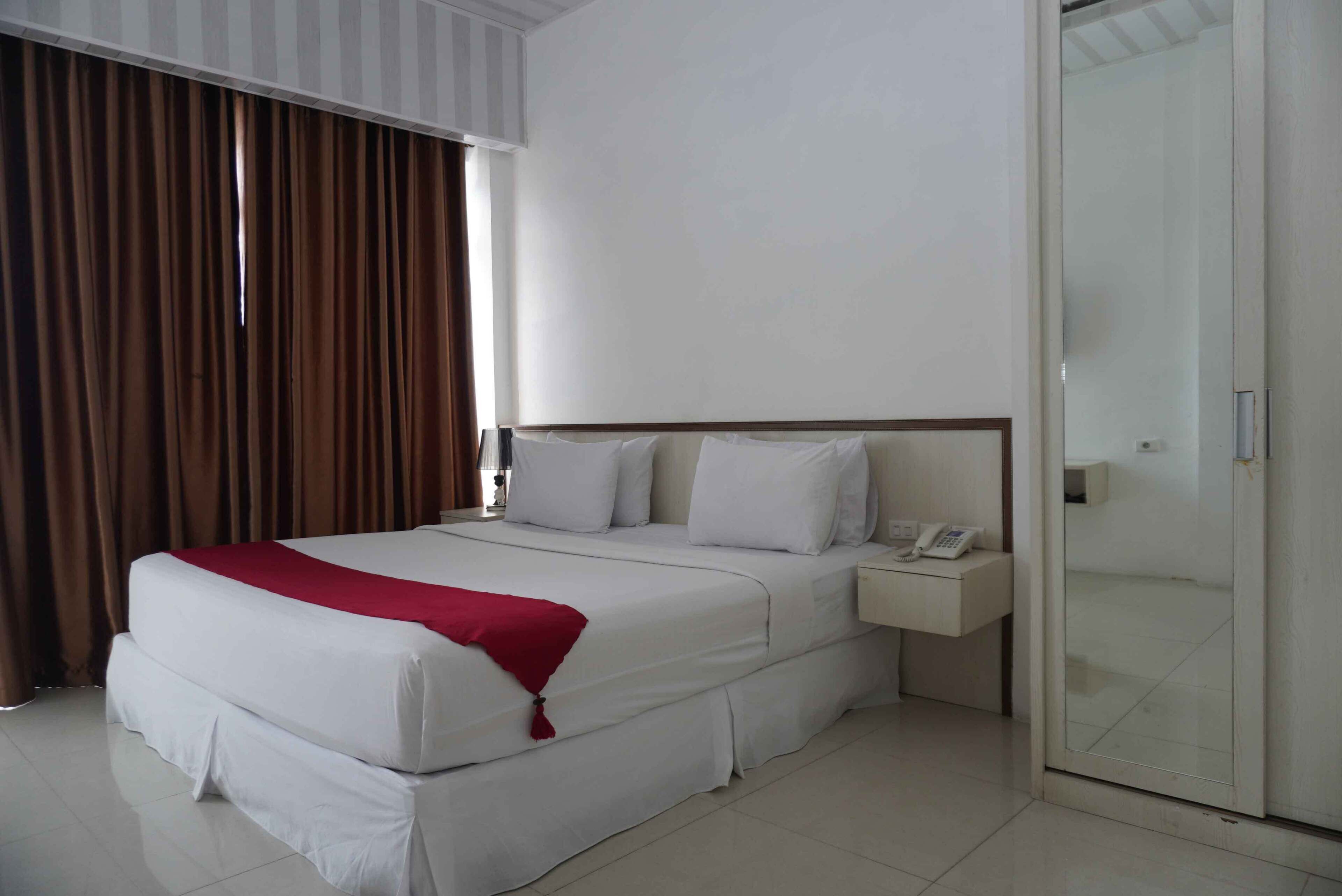 Een hotelkamer met een groot bed, een nachtkastje met een telefoon en een schuifdeur van glas.