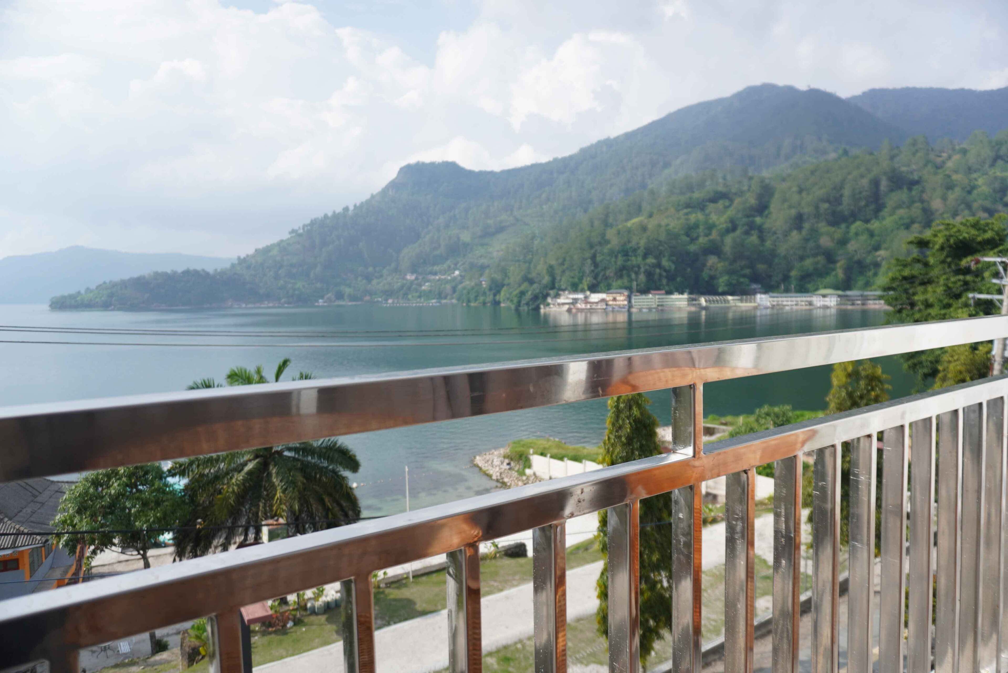 A balcony with a view of a lake, mountains, and a distant shoreline.