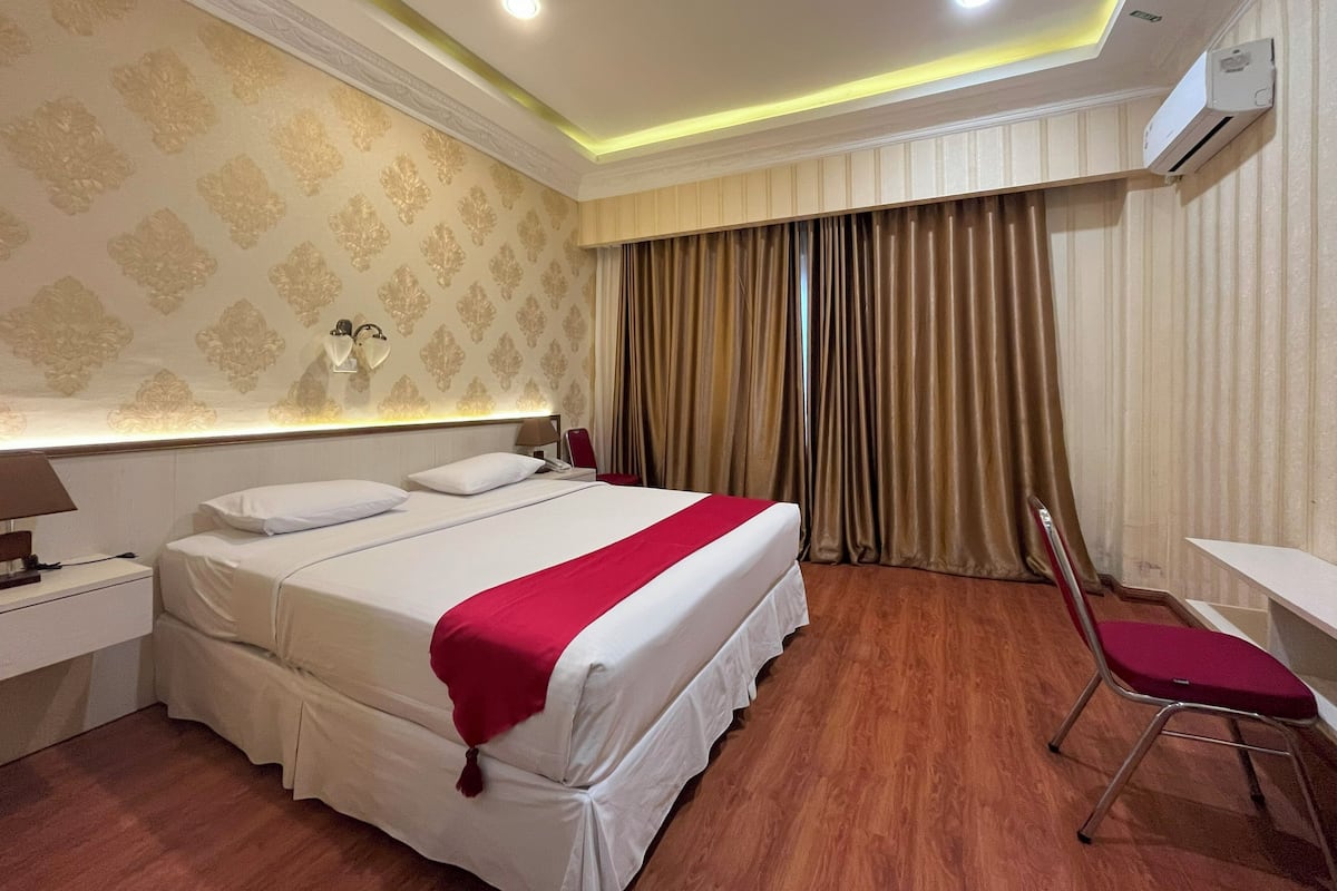 Una habitación de hotel con una cama grande, un escritorio y una silla.