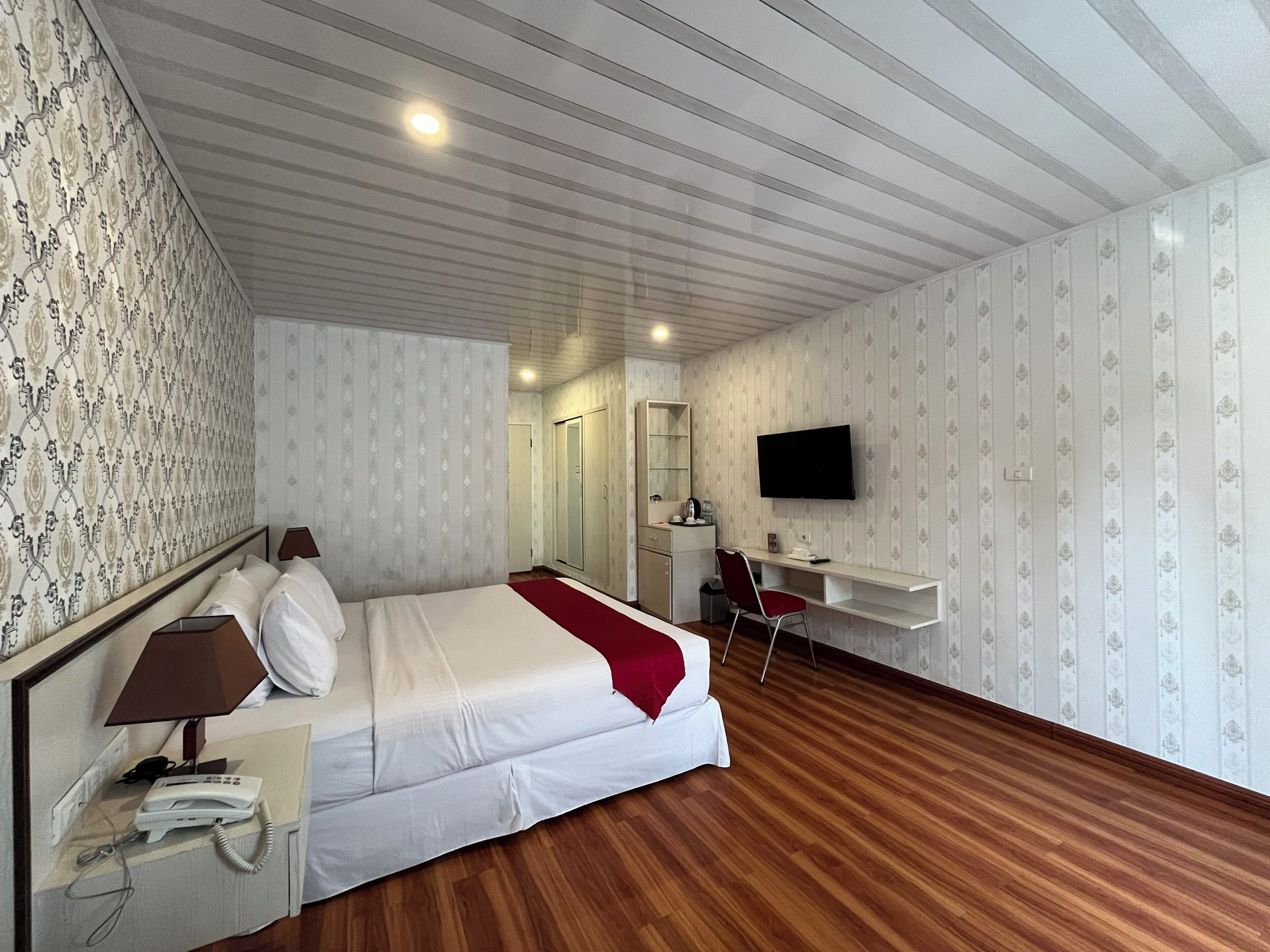 A hotel room with a bed, a desk, a television, and a telephone.