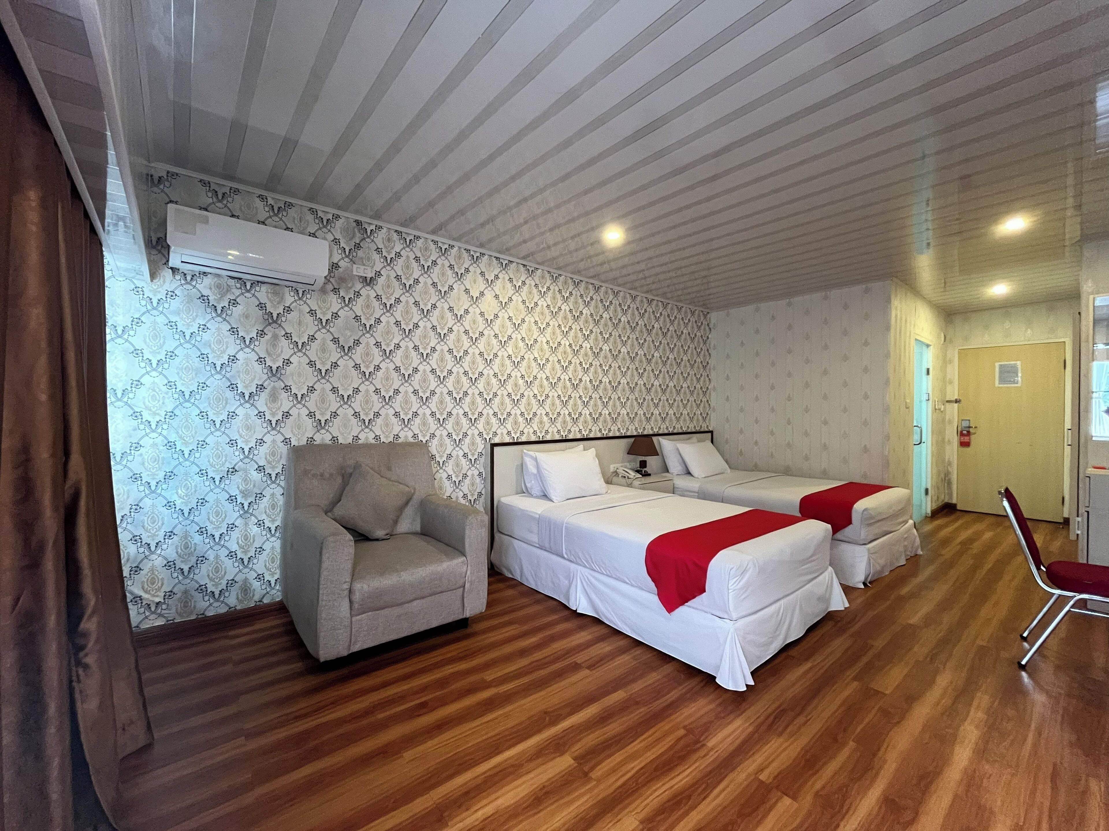 A room with two beds, a chair, and a wooden floor.