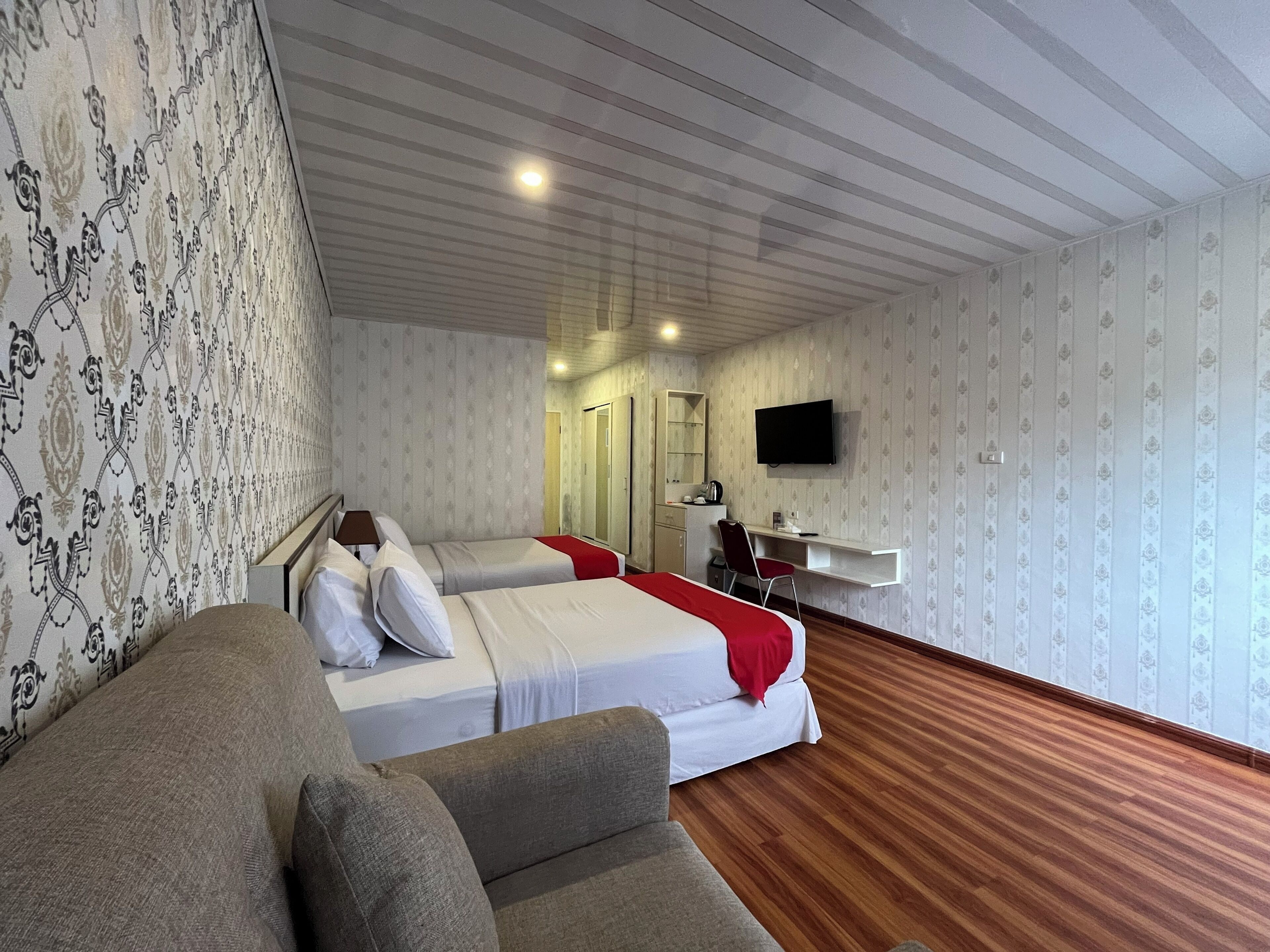 A hotel room with two beds, a TV, a desk, and a wardrobe.