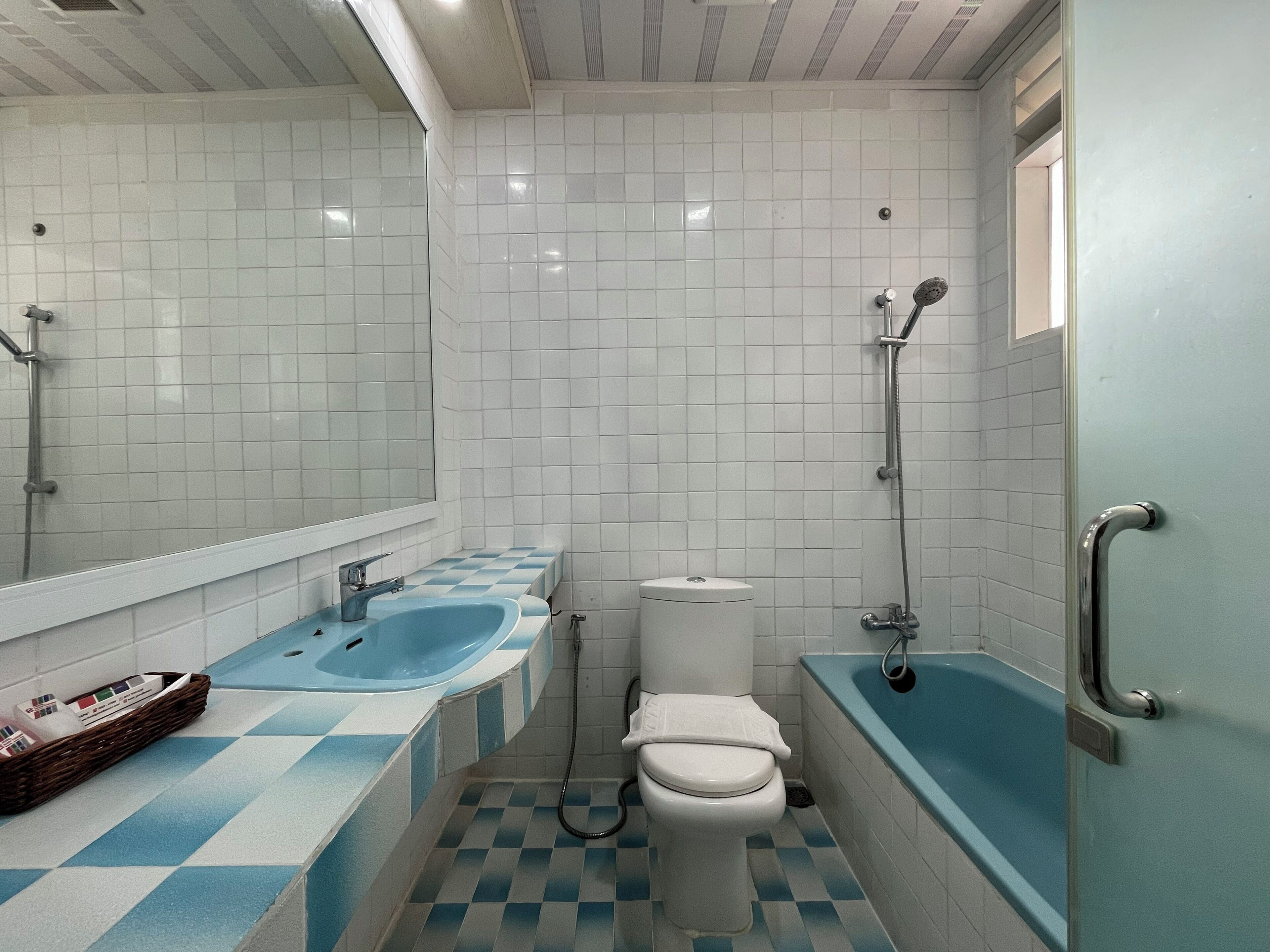 A bathroom with a white toilet, a blue sink, and a bathtub.
