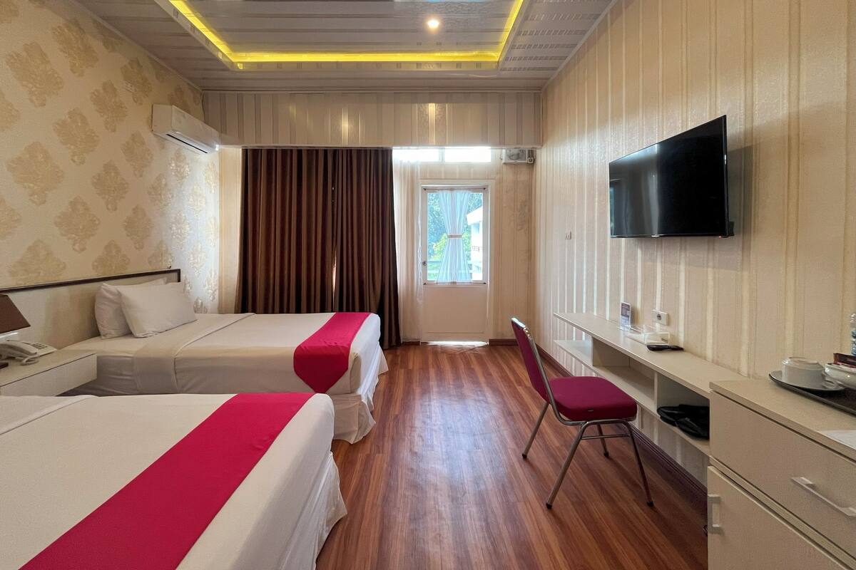 Una habitación de hotel con dos camas, televisión, escritorio y una silla.