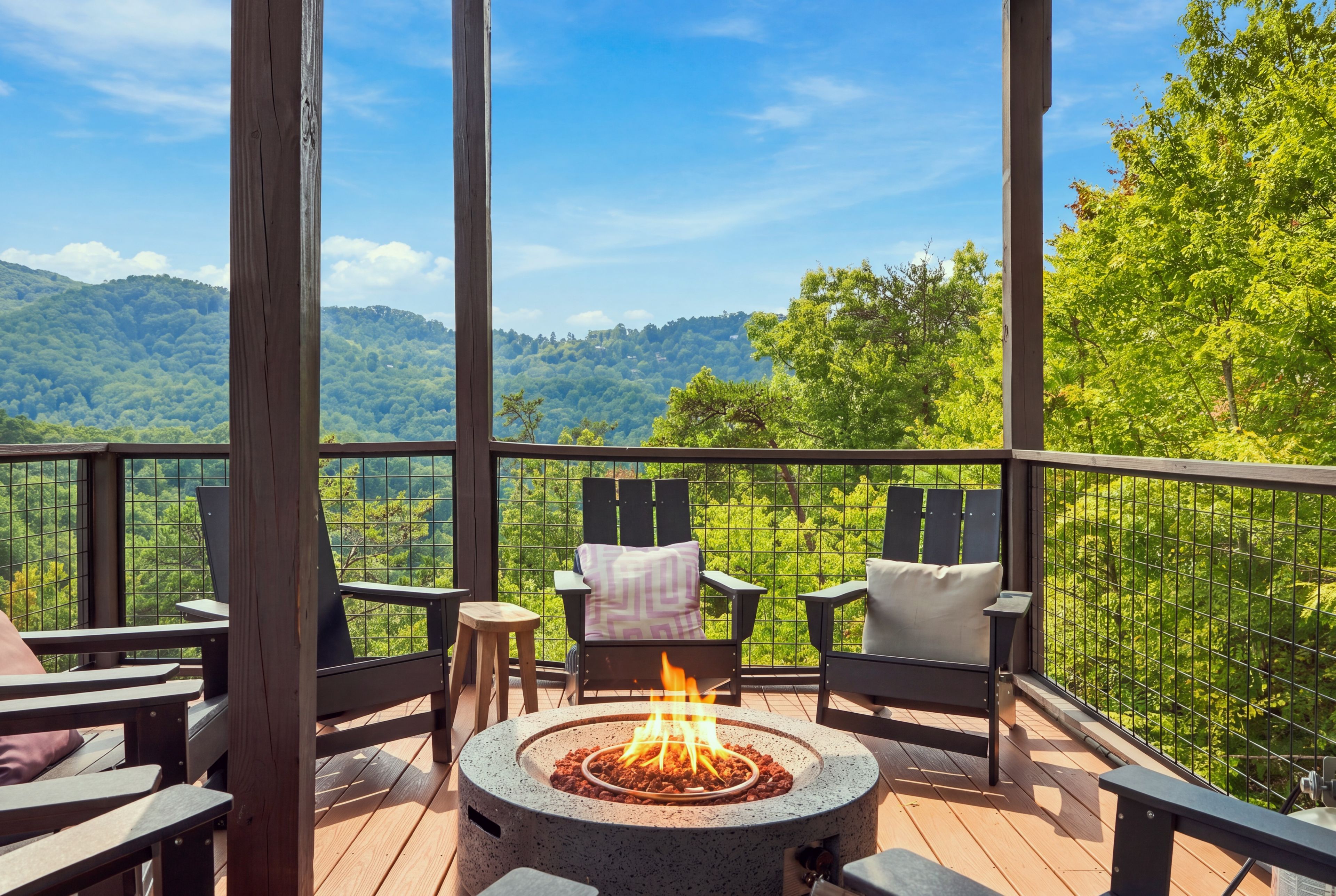 A deck with a fire pit, seating, and a view of a forested mountain.