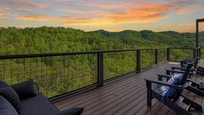 Una terrassa de fusta amb seients exteriors i vista a un paisatge forestal.