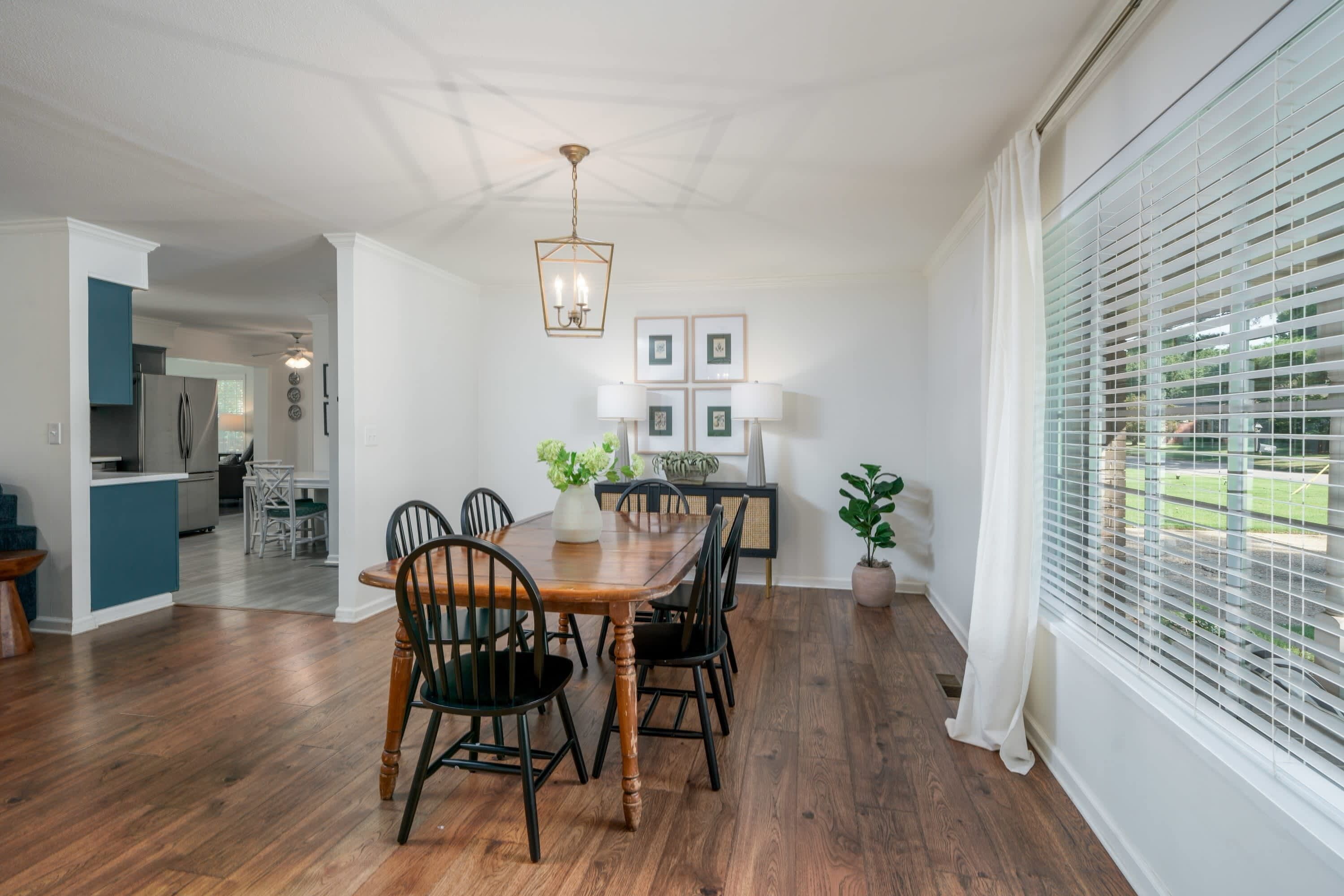 Un coin repas avec une table et des chaises en bois, un lustre et des tableaux encadrés au mur.