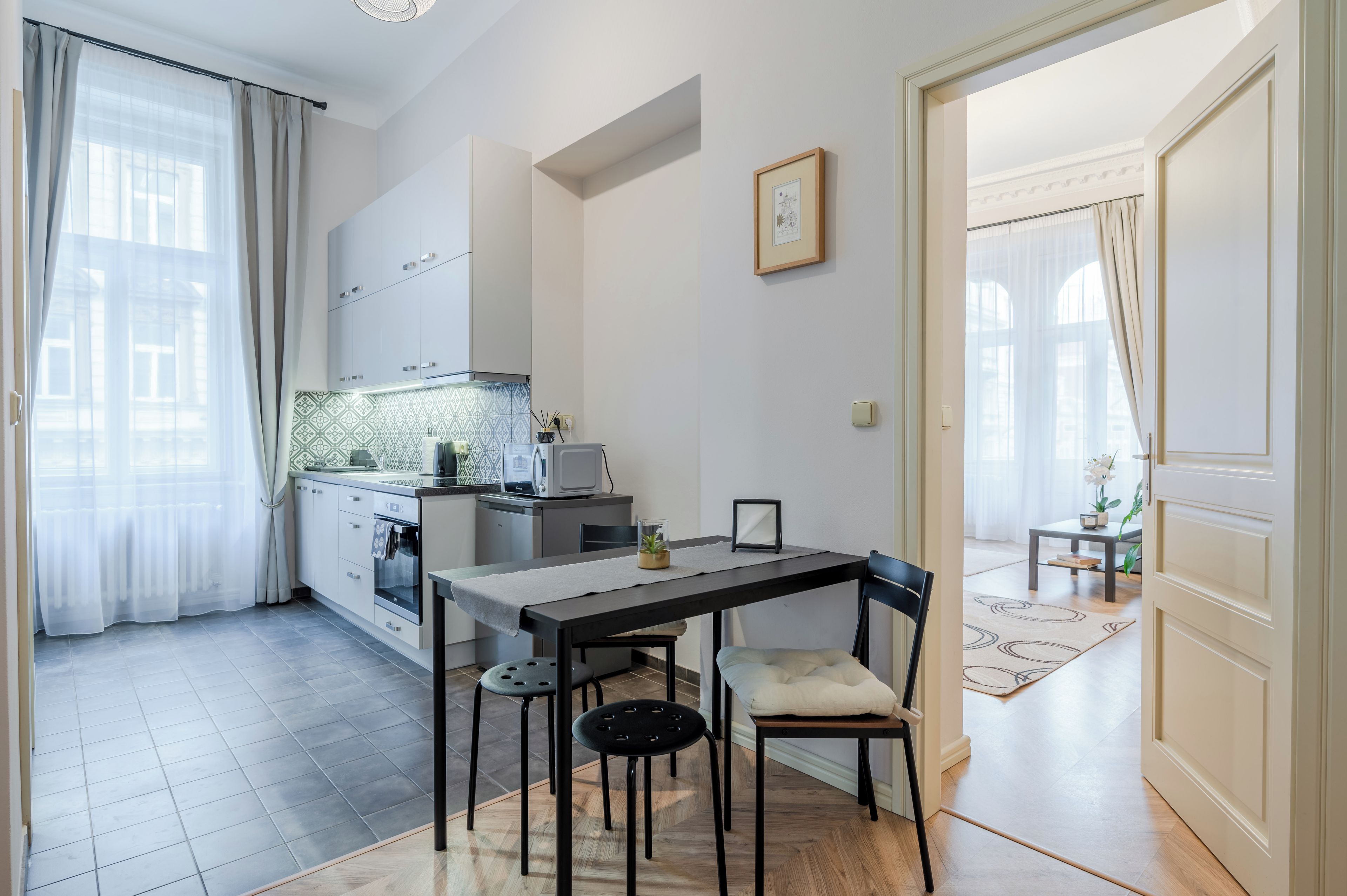 Une cuisine compacte dotée d’appareils électroménagers modernes, un coin repas avec une table et des chaises, et une vue sur l’extérieur par une fenêtre.