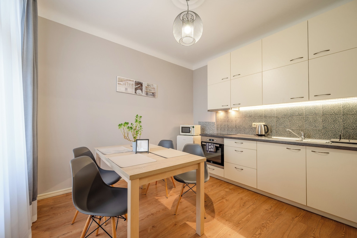 A modern kitchen with a dining table, chairs, a microwave, an oven, and a sink.