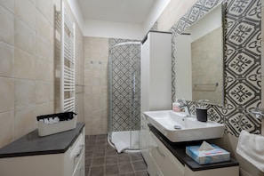 Un baño moderno con ducha, lavamanos y toallero.