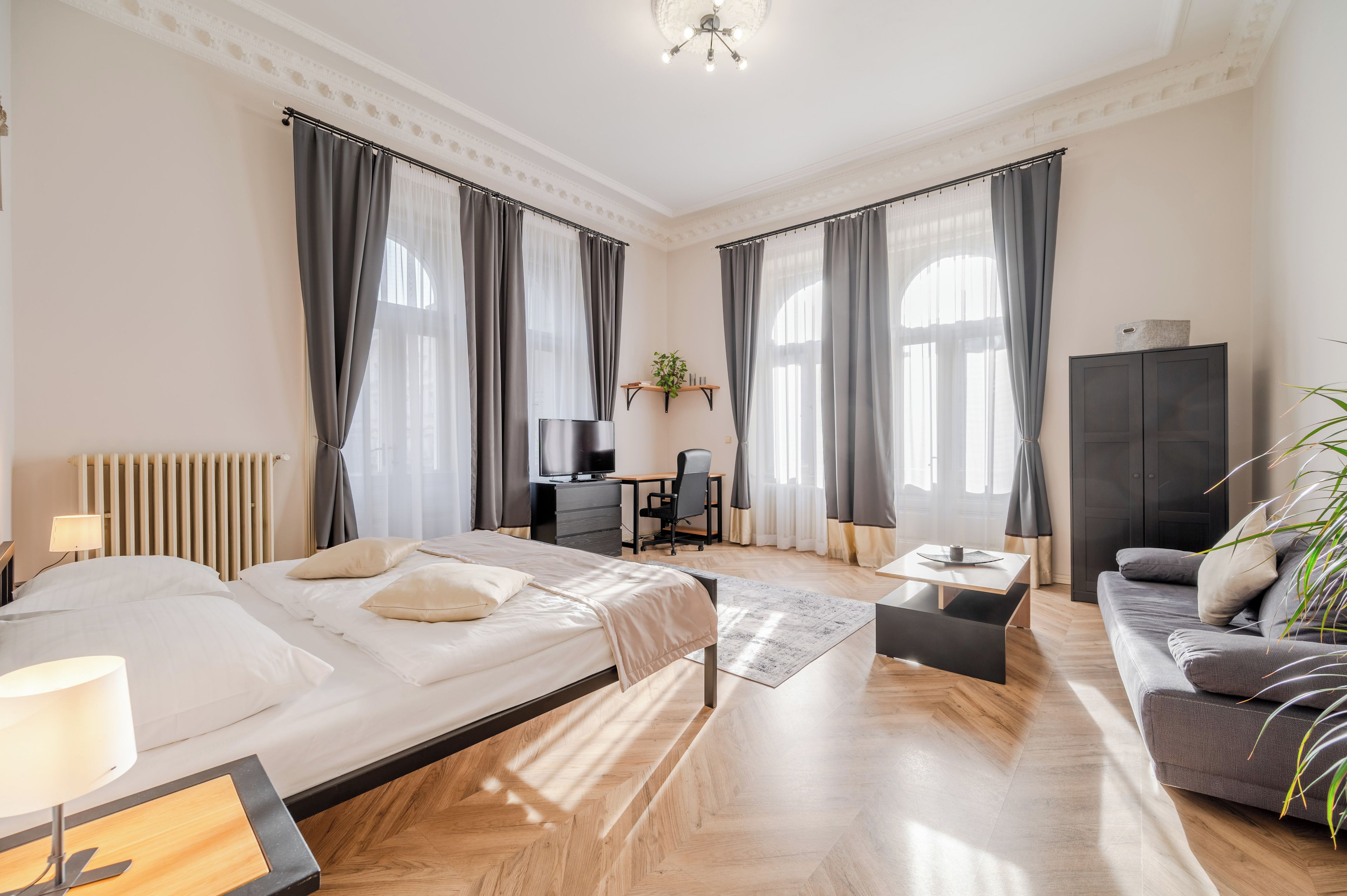 Une chambre d’hôtel avec un lit, un bureau, un canapé et une télévision.