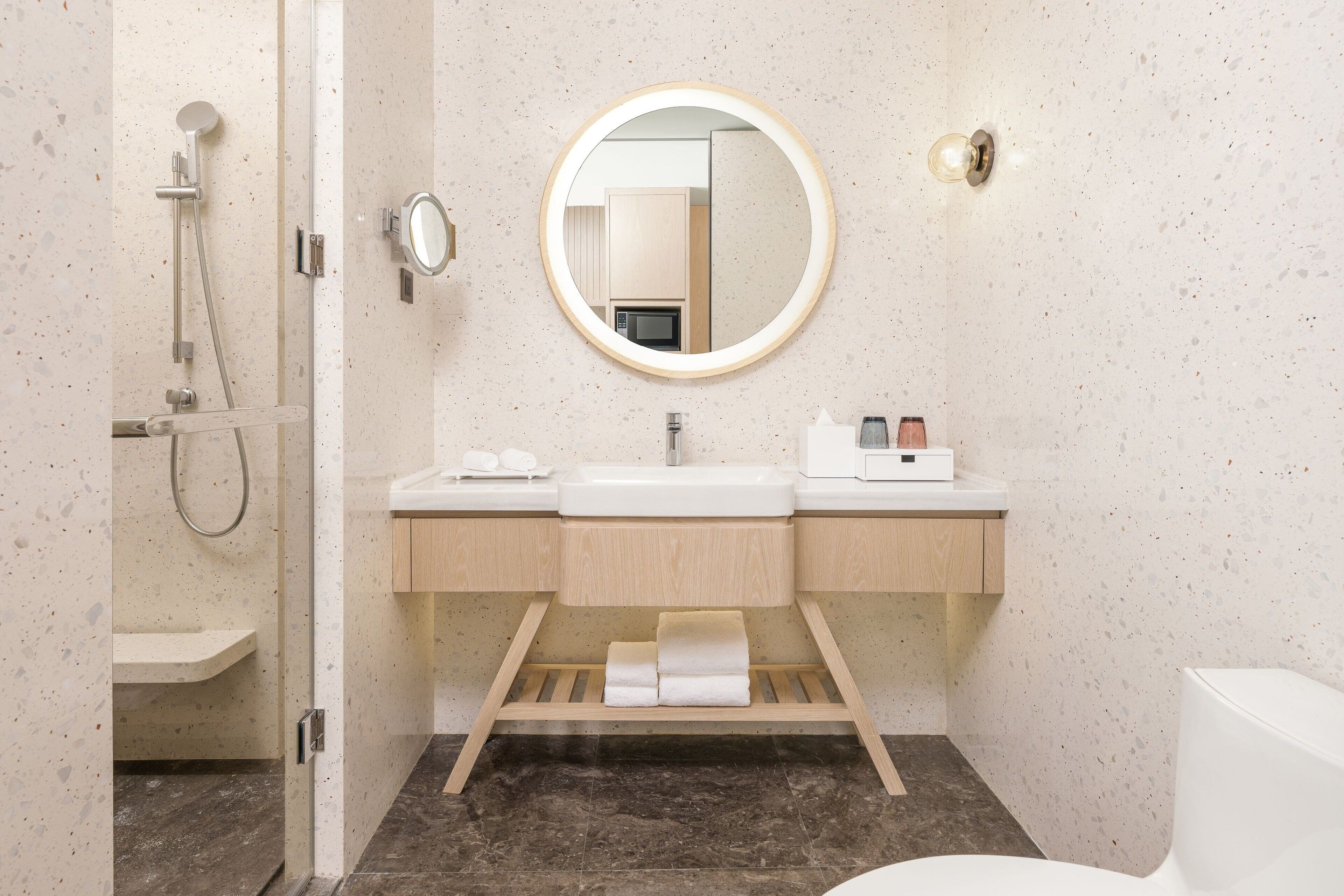 A modern bathroom with a shower, a sink with a mirror, and a toilet.
