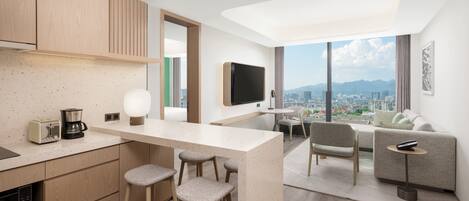 A modern kitchen with a bar area, a dining set, and a sofa.