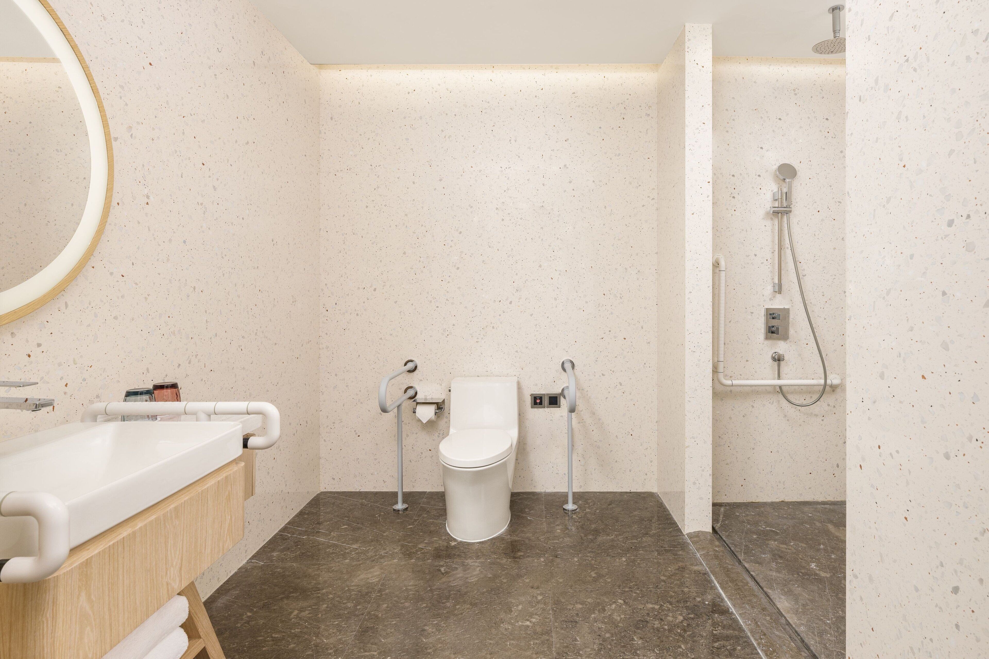 Ein modernes Badezimmer mit Waschbecken, Toilette und Dusche, alles in Weiß.