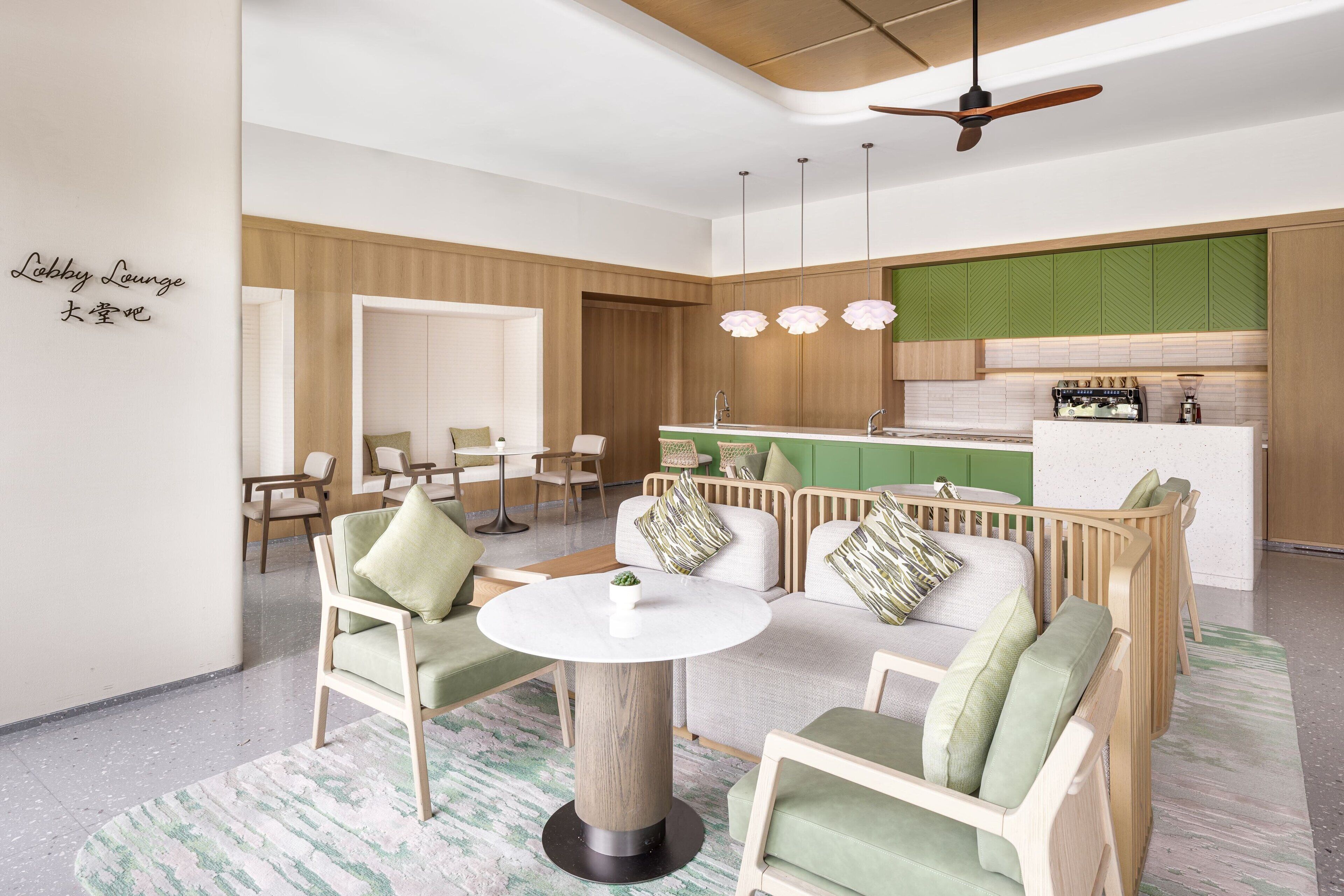 A modern lounge with a round table, sofas, and a kitchenette area.