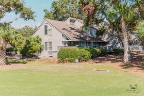 A two-story house with a porch, surrounded by greenery and trees. - 255 Turnberry-Fazio Course Views, Dog Friendly, Free Tennis (Hilton Head Island)