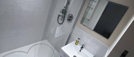 Een moderne badkamer met een douchecabine van glas, een wit bad en een wastafel met spiegel.