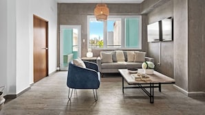 A modern living room with a sofa, a blue armchair, a coffee table, and a hanging light fixture. - Boho Loft | Modern & Chic in Santurce (San Juan)