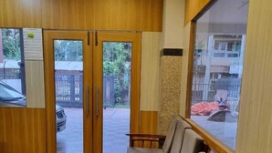 Un espace d’accueil avec un lambris en bois, un sol à carreaux et un coin salon avec des fauteuils confortables.