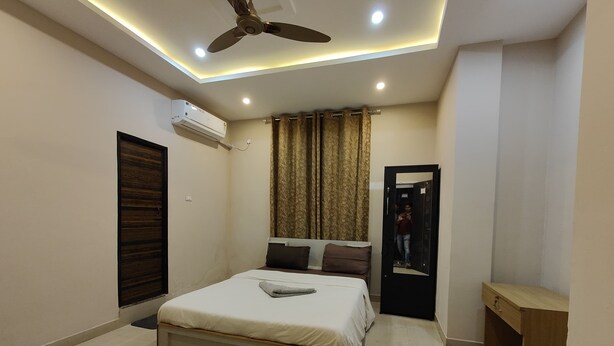 Une chambre moderne équipée d’un lit, d’un ventilateur de plafond, d’un climatiseur et d’un miroir.