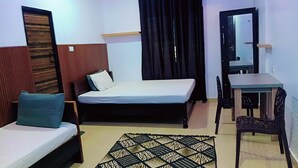 Une chambre avec deux lits, un bureau et un mur décoré d’un motif.