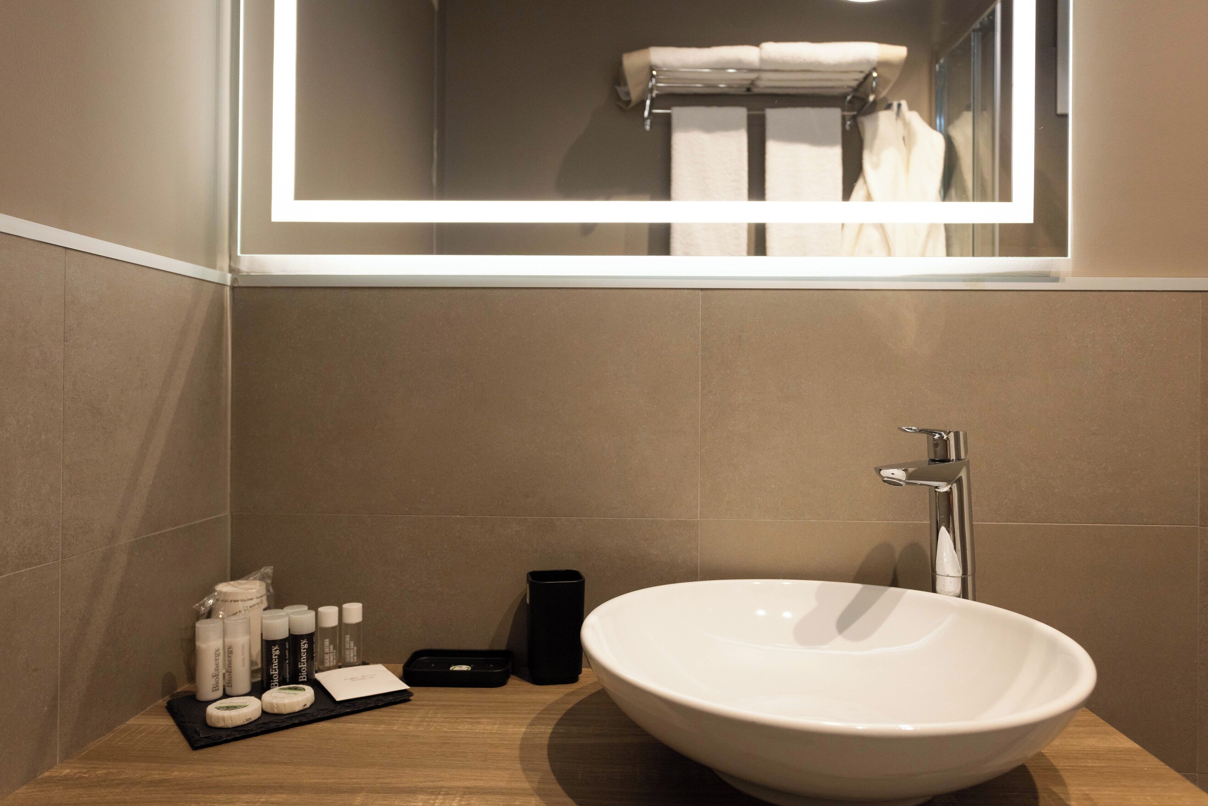 A modern bathroom with a large white sink, a mirror above the sink, and toiletries on a tray.