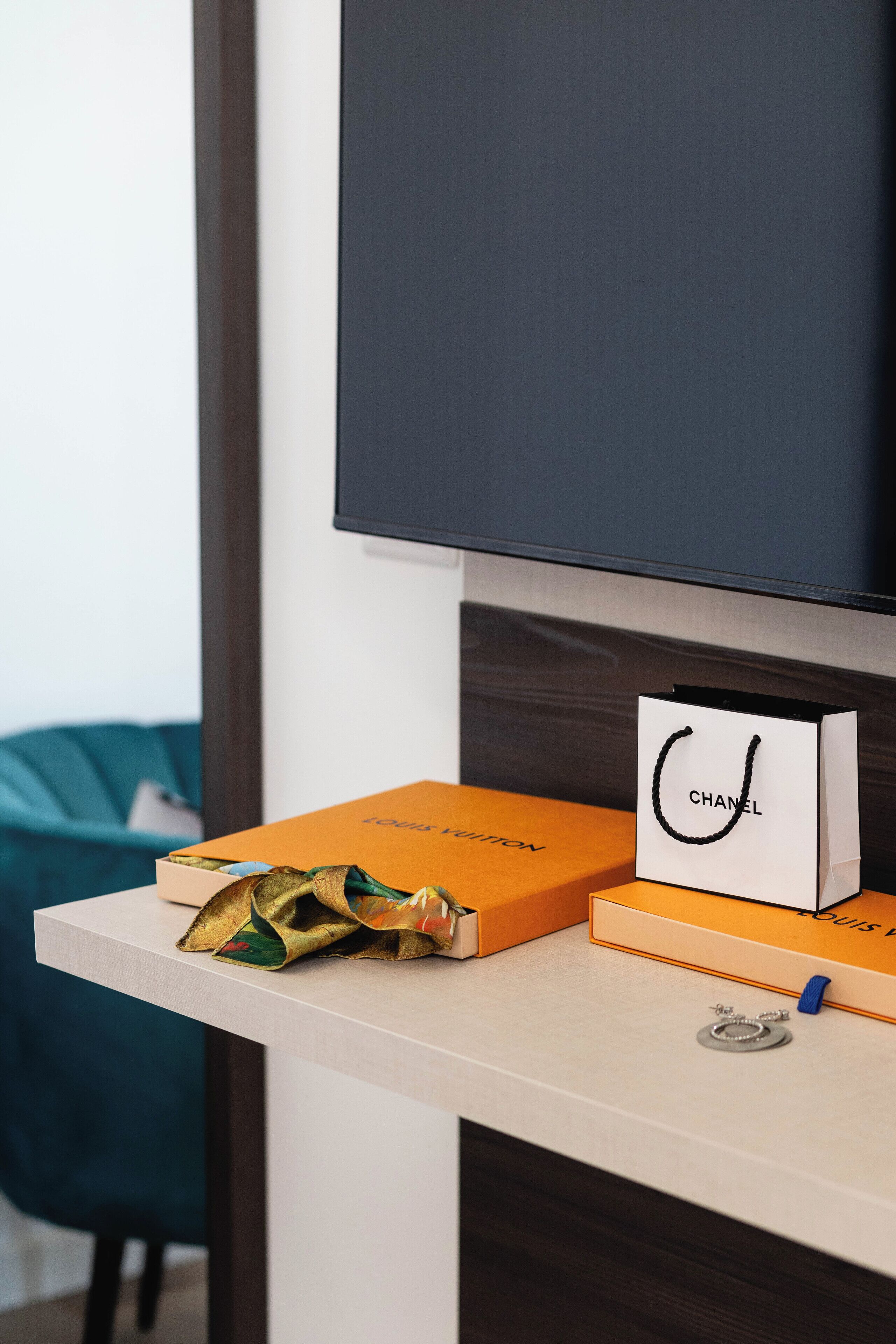 Un escritorio con un televisor, un bolso Chanel y cajas de Louis Vuitton.