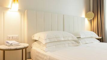 Una habitación de hotel con una cama, una mesita de noche con teléfono y una lámpara fijada a la pared.
