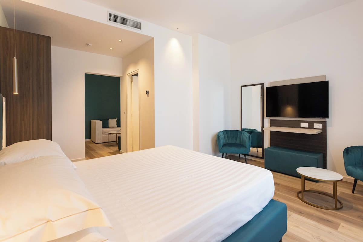 A modern hotel room with a large bed, a TV mounted on the wall, and a small round table.