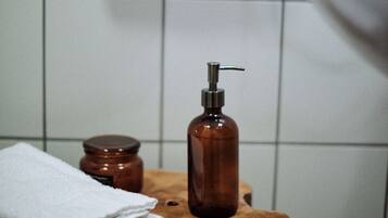 A small stool holds a bottle with a pump dispenser and a labeled jar.