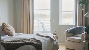 A bedroom with a bed, a chair, a window, and a plant. - Vallevikens Hotell och Restaurang  (Lärbro)