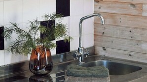 A modern kitchen with a stainless steel sink, a wooden backsplash, and white cabinets. - Vallevikens Hotell och Restaurang  (Lärbro)
