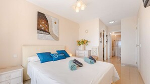 Ein Schlafzimmer mit einem Bett, einem Nachttisch, einer Wanduhr, einem Gemälde und einem Flur, der zu einem Badezimmer führt.