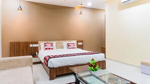 Ein Hotelzimmer mit Bett, Nachttischen, einem Glastisch mit Blumenvase, Deckenventilator und Klimaanlage.