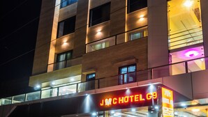 Ein Hotel mit mehreren Etagen, beleuchteten Fenstern und einer auffälligen Neonreklame.