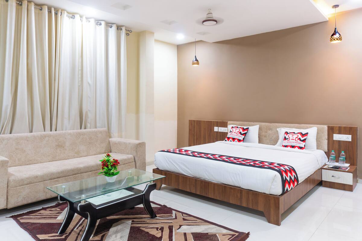 Una habitación de hotel moderna con una cama, una mesa de centro de vidrio, un sofá y una mesita de noche.