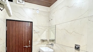 Ein modernes Badezimmer mit einer Holztür, einem weißen Waschbecken und einer weißen Toilette.