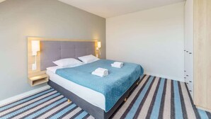 Una habitación de hotel moderna con cama, lámparas de noche, mesitas de noche y alfombra a rayas.