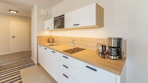 Una cocina moderna con encimera de madera, electrodomésticos de acero inoxidable y armarios blancos.