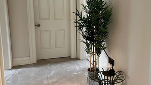 A hallway with a marble floor, a white door, a potted plant, and a framed picture on the wall. - Plantation Drive - Home from home (Limavady)