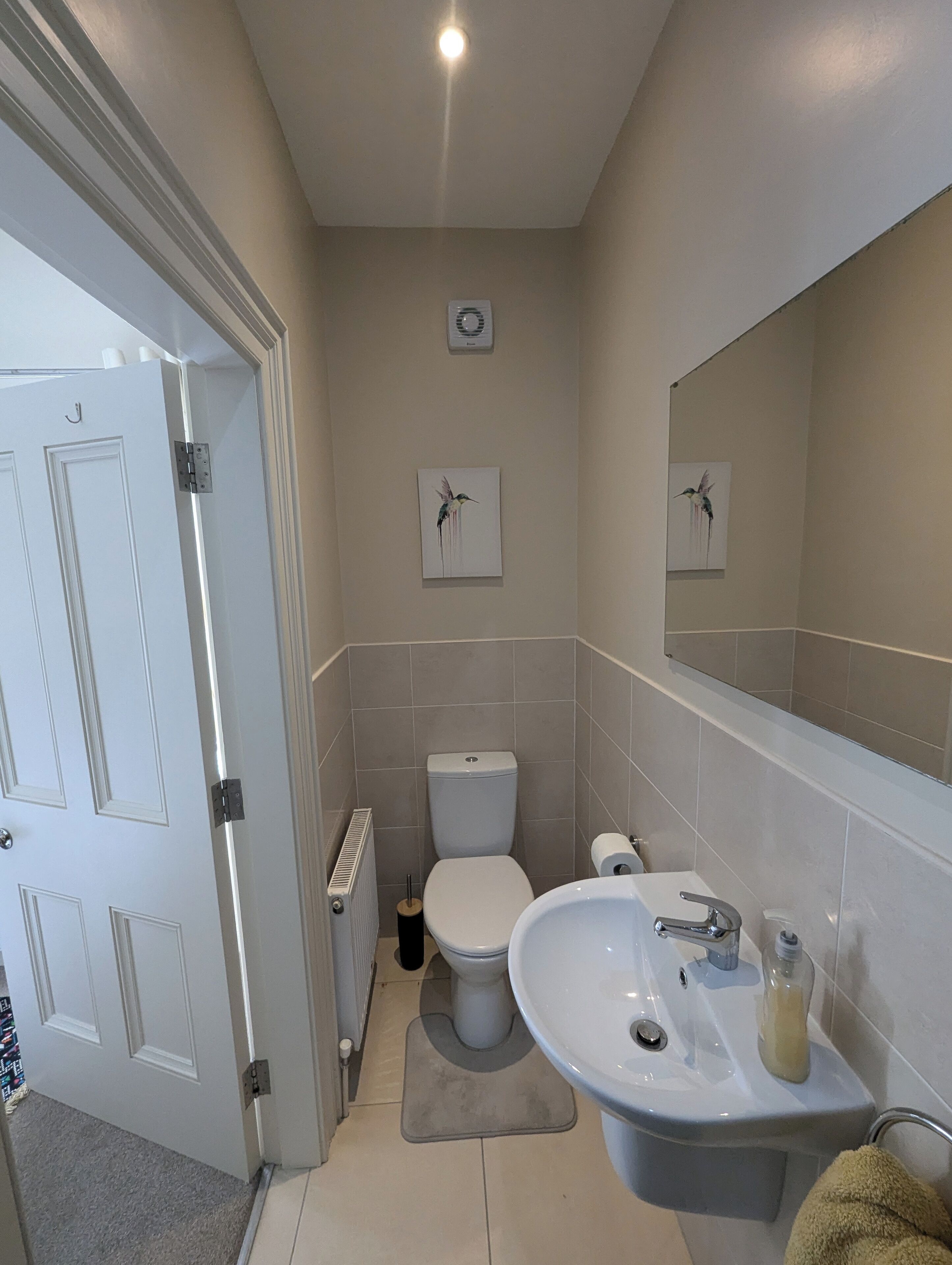 A compact bathroom with a toilet, sink, and mirror.