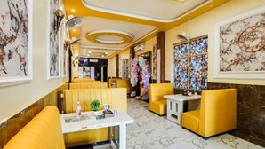 A restaurant with yellow booths, marble floors, and decorative ceiling lights. - Hotel Aadhya & Restaurant (Auraiya)