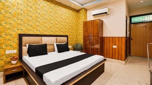 A hotel room with a large bed, wooden wardrobe, and patterned wallpaper. - Hotel Aadhya & Restaurant (Auraiya)
