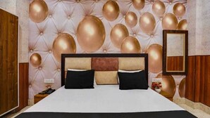 A bedroom with a tufted headboard, a large bed, and a mirror on the wall. - Hotel Aadhya & Restaurant (Auraiya)