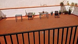 A balcony with a table and chairs, potted plants, and a white wall. - Posada Madrileña (Madrid)